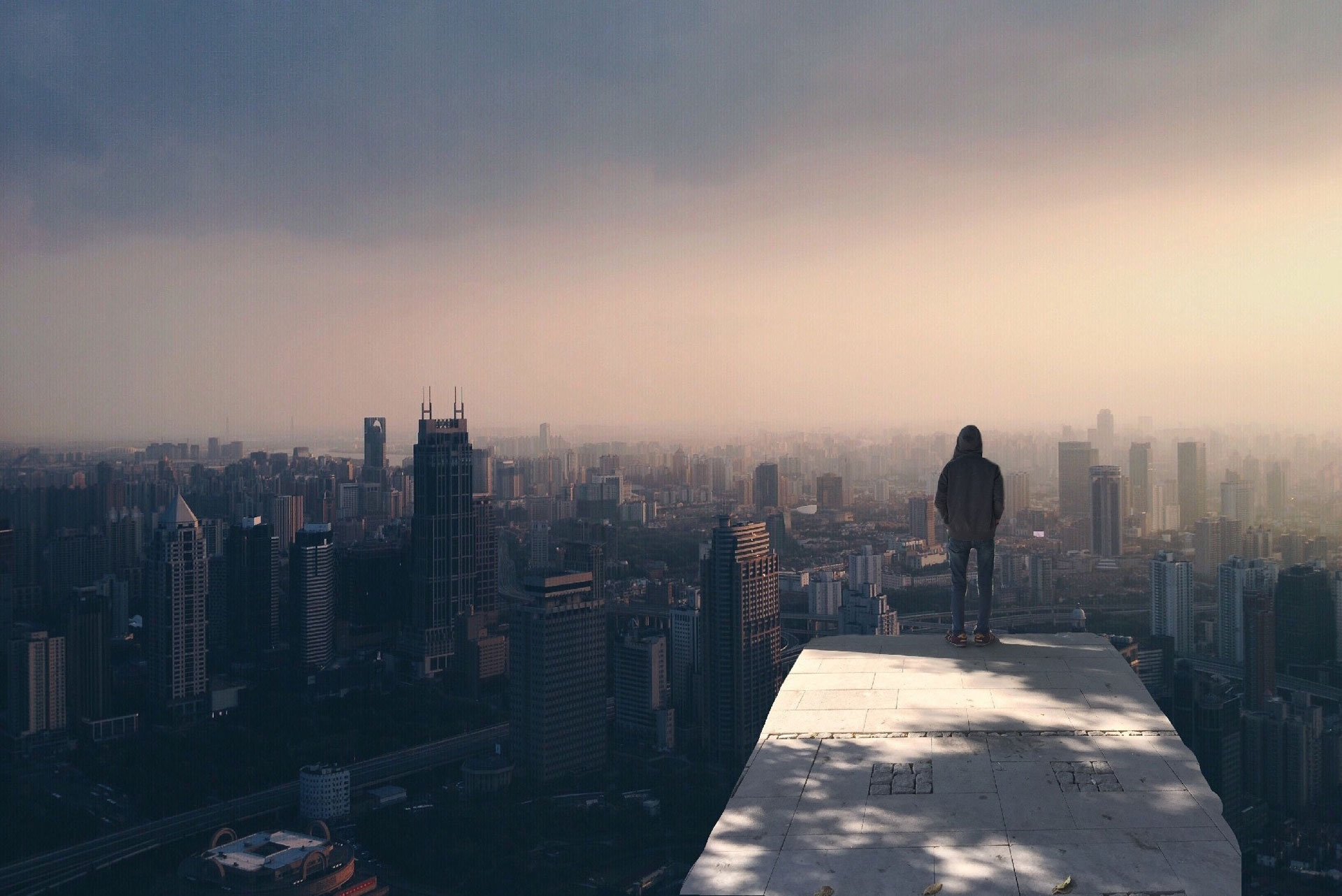 Man seen from the back on top of a building looking at the city in front of him